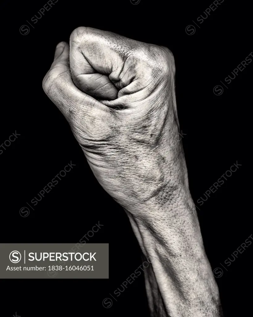 Mid-Adult Woman's Clenched Fist against Black Background, Profile View