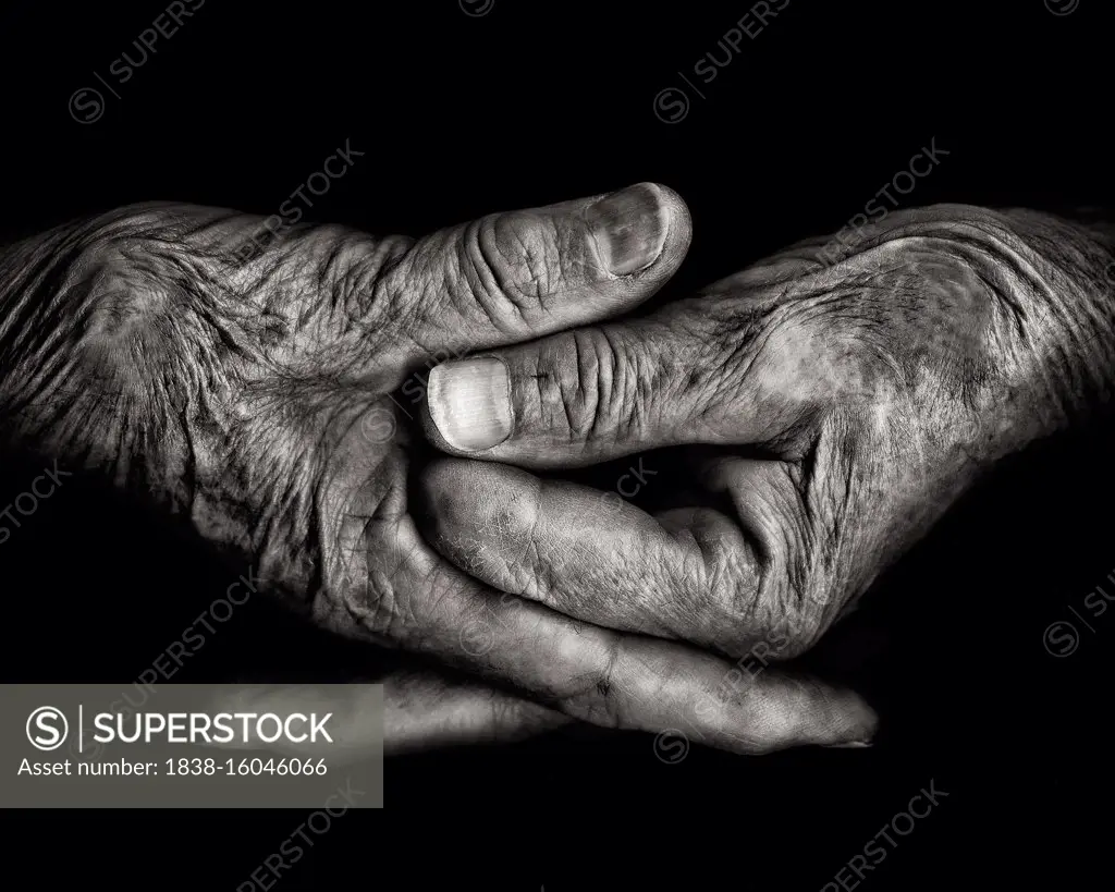 Two Wrinkled Hands against Black Background