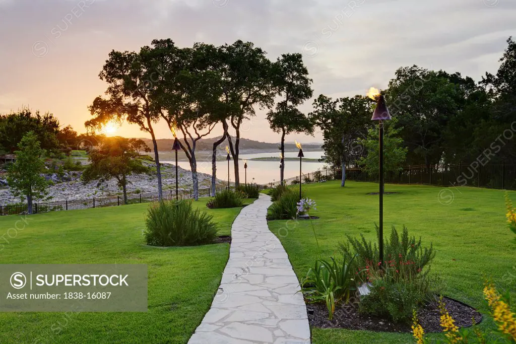 Stone Path to Water Lined with Tiki Torches at Sunset