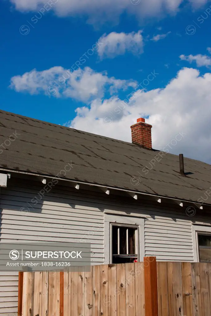 Rear View of House with Tar Paper Roof Against Blue Sky