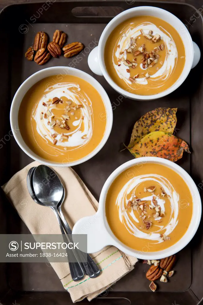Three Bowls of Pumpkin Soup with Sour Cream on Tray, High Angle View