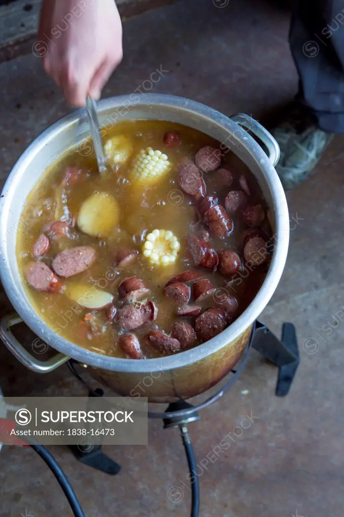 Person Cooking Low Country Boil with Corn and Sausages