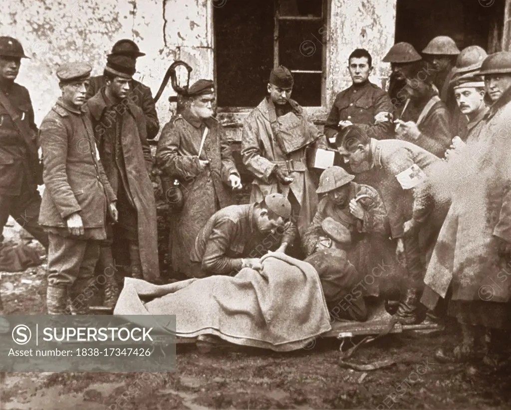 Lieutenant C.S. Darley, a Catholic chaplain, treating German officer lying on Stretcher outside Building, 89th Division Dressing Station, near Remonville, France, U.S. Army Signal Corps, November 2, 1918