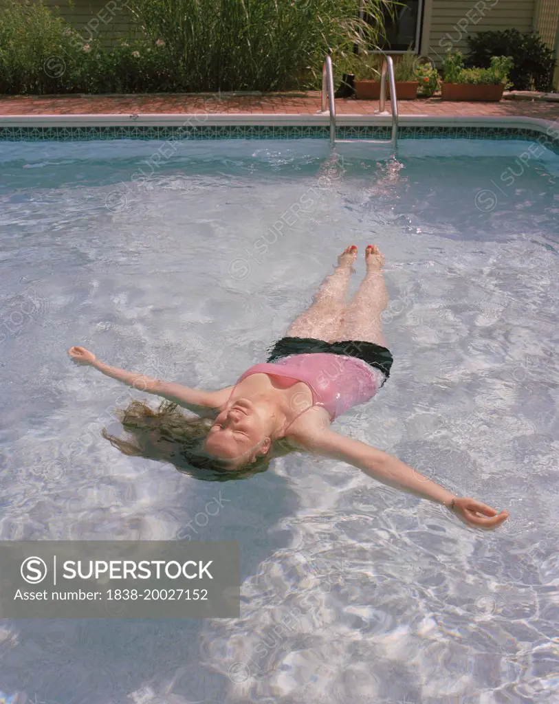 Woman Floating on Back in Swimming Pool