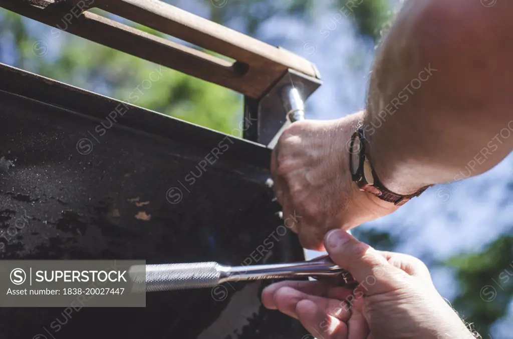 Close-up of Man's Hands with Ratchet Wrench Fixing Outdoor Grill