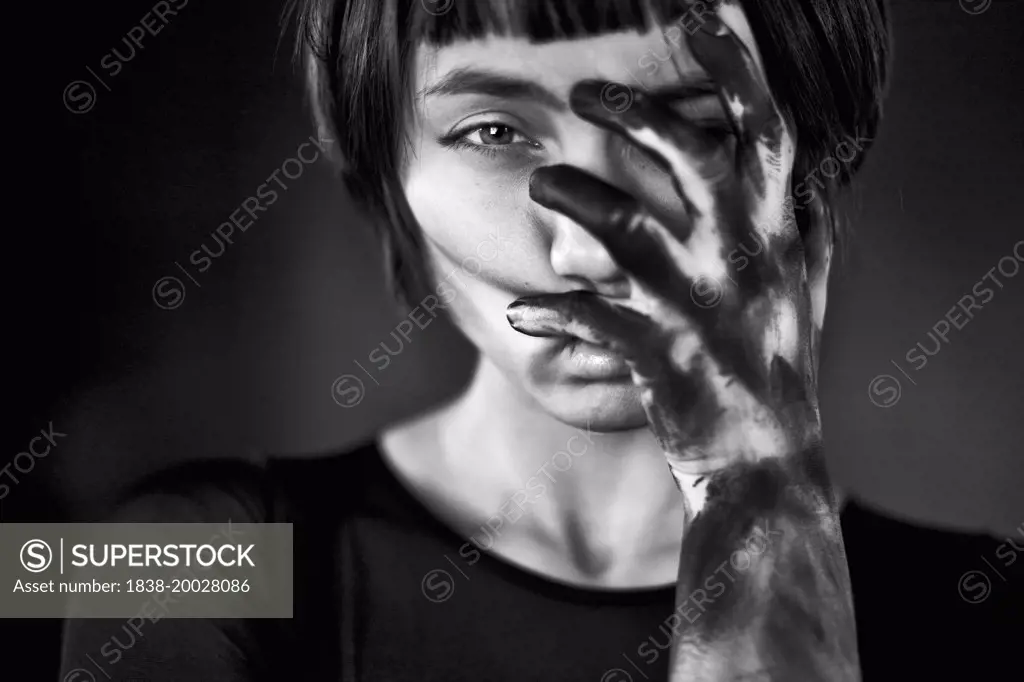 Portrait of Young Woman with Black Paint on Hand Covering  Face