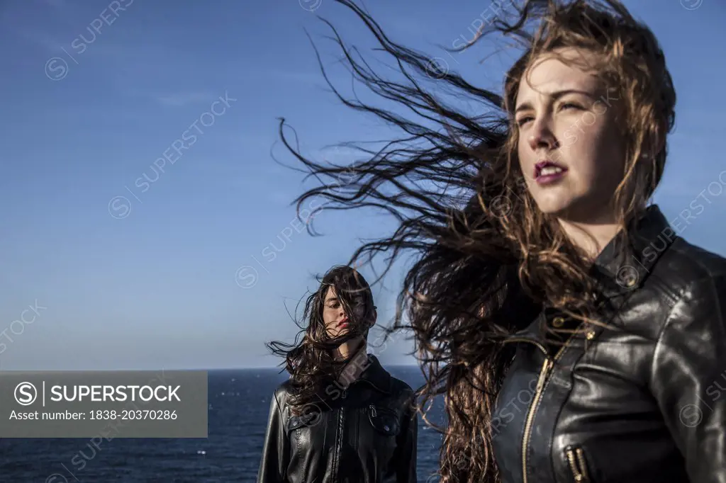 Two Young Women with Hair Blowing in Wind by Sea