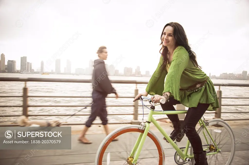 Portrait of Smiling Woman on Bicycle Near River, New York City, USA