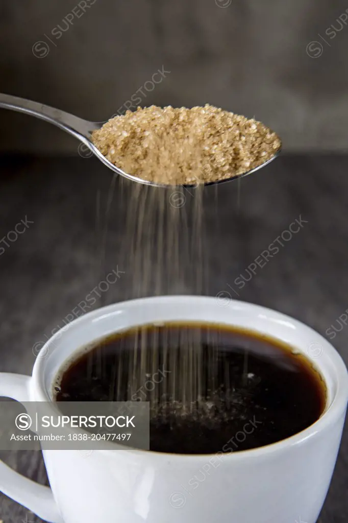 Brown Sugar Being Poured into Cup of Coffee
