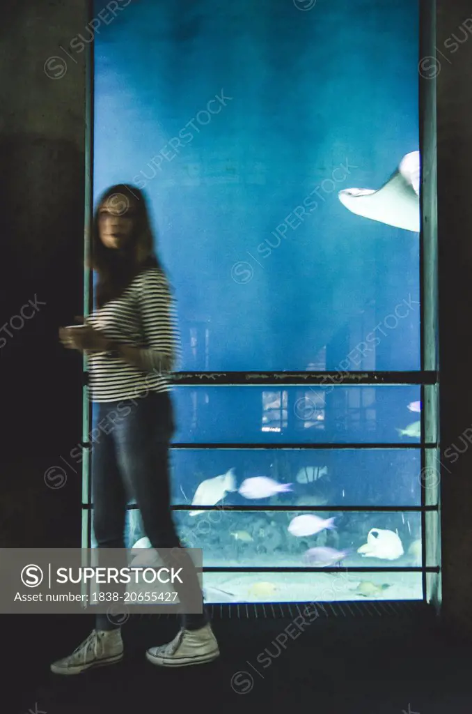 Motion-Blurred Young Adult Woman Walking Past Exhibit, National Aquarium, Baltimore, Maryland, USA