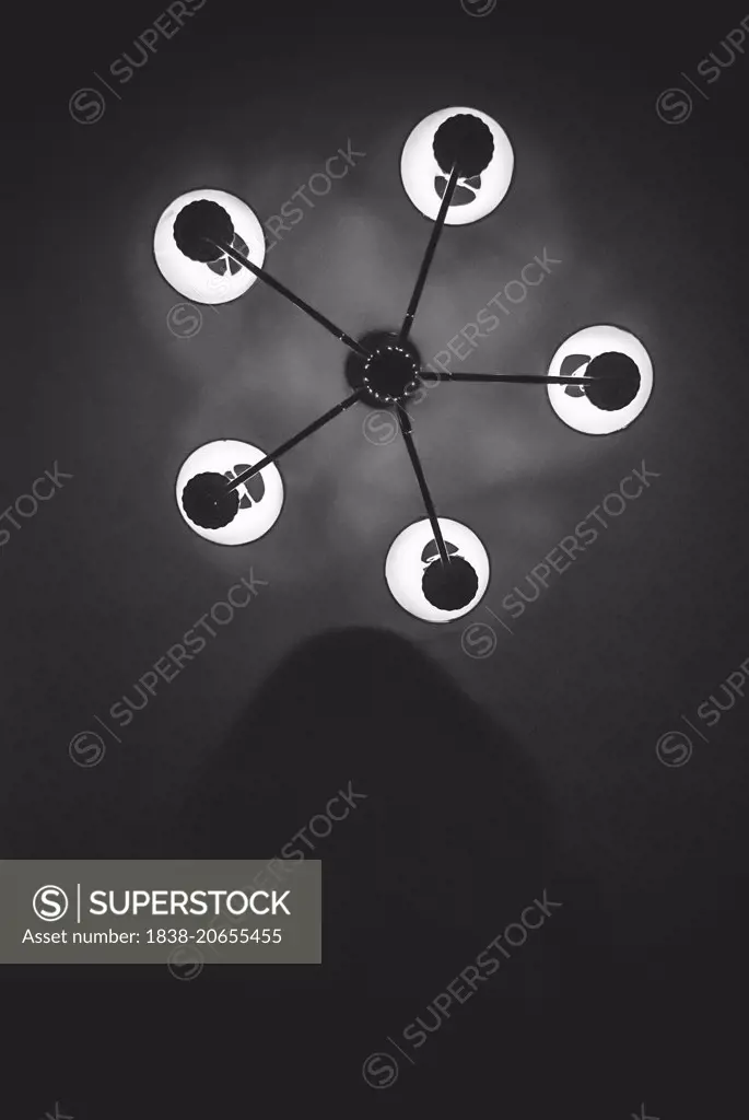 Shadowy Figure Beneath Ceiling Lamp at Night