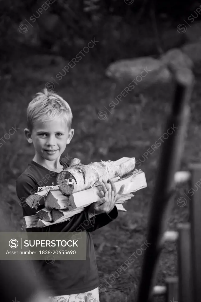 Young Boy Holding Stack of Wood