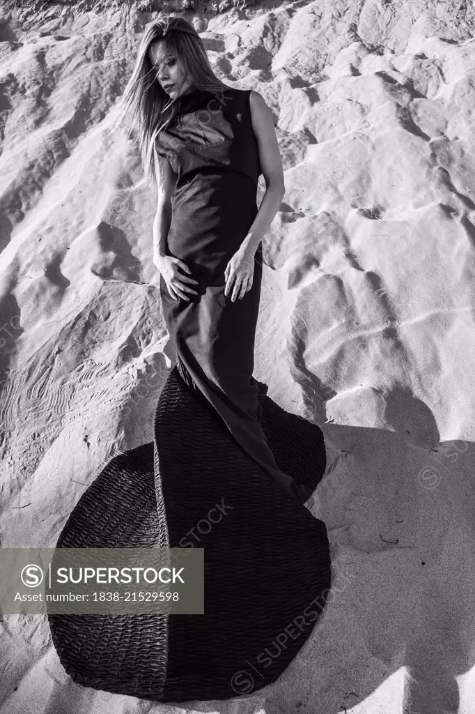 Outdoor Fashion Portrait of Young Adult Woman in Long Black Dress on Sand Dune