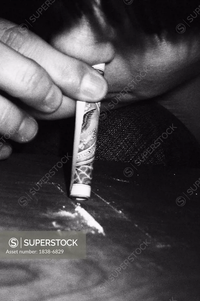 Person Snorting Line of Cocaine Through Dollar Bill