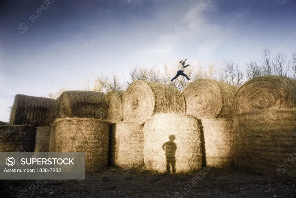 Person Running Across Top of Large Hay Bales and Shadow