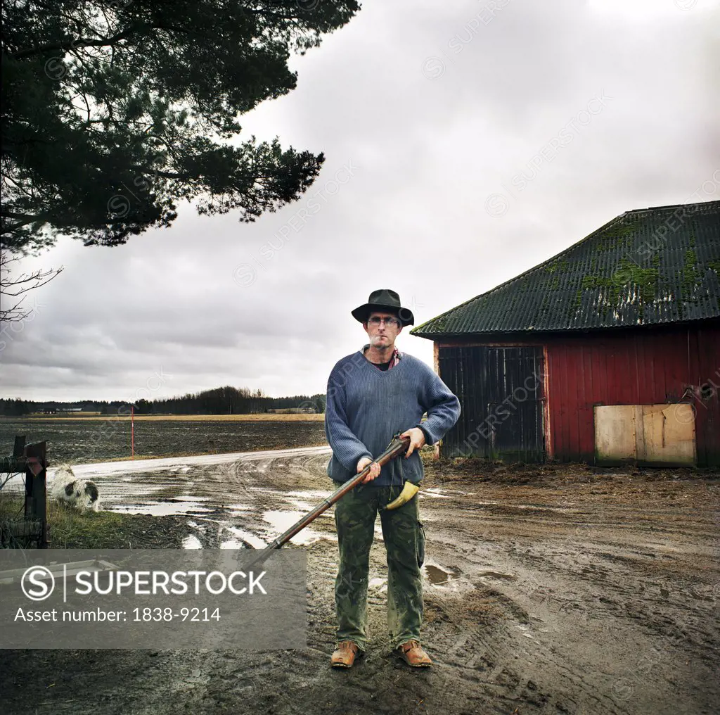 Man Holding Rifle on Farm