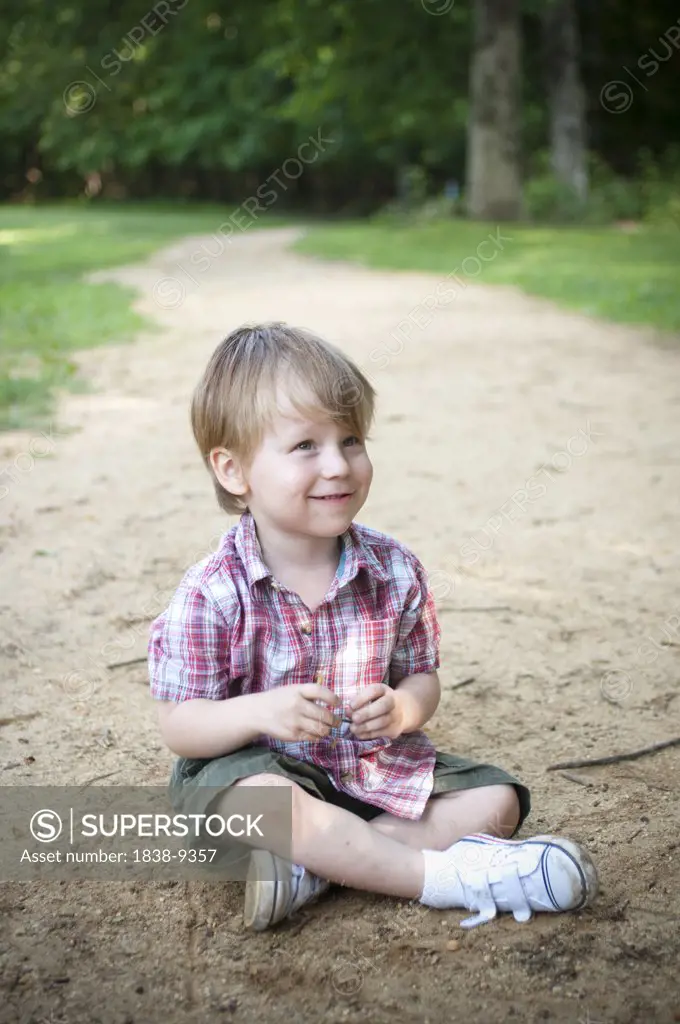 Smiling Young Boy Sitting on Ground