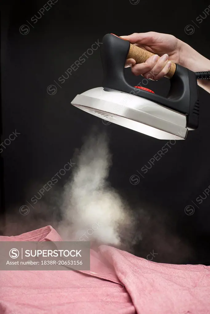 Hand Holding Steam Iron above Man's Dress Shirt