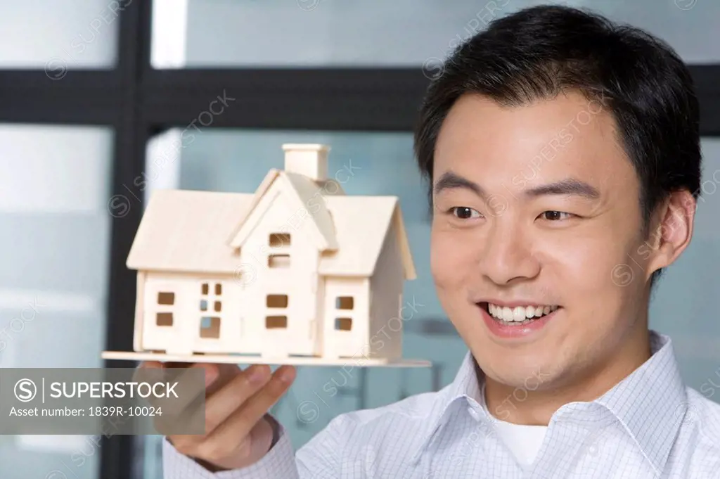 Young man holding a house model