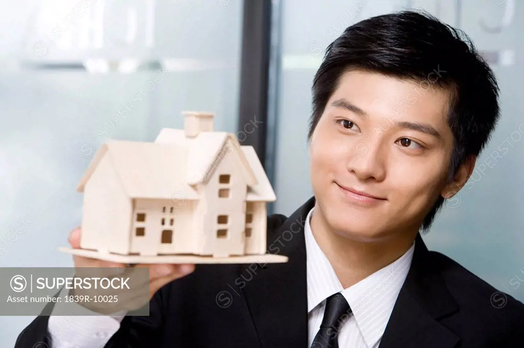 Young man holding a house model