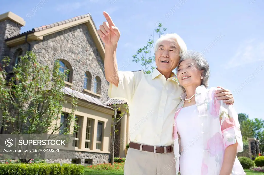 Senior couple standing in front of house