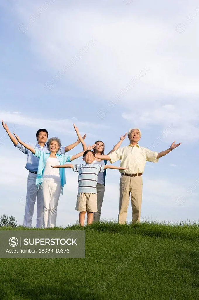 Family standing on the grass, arms out_stretched