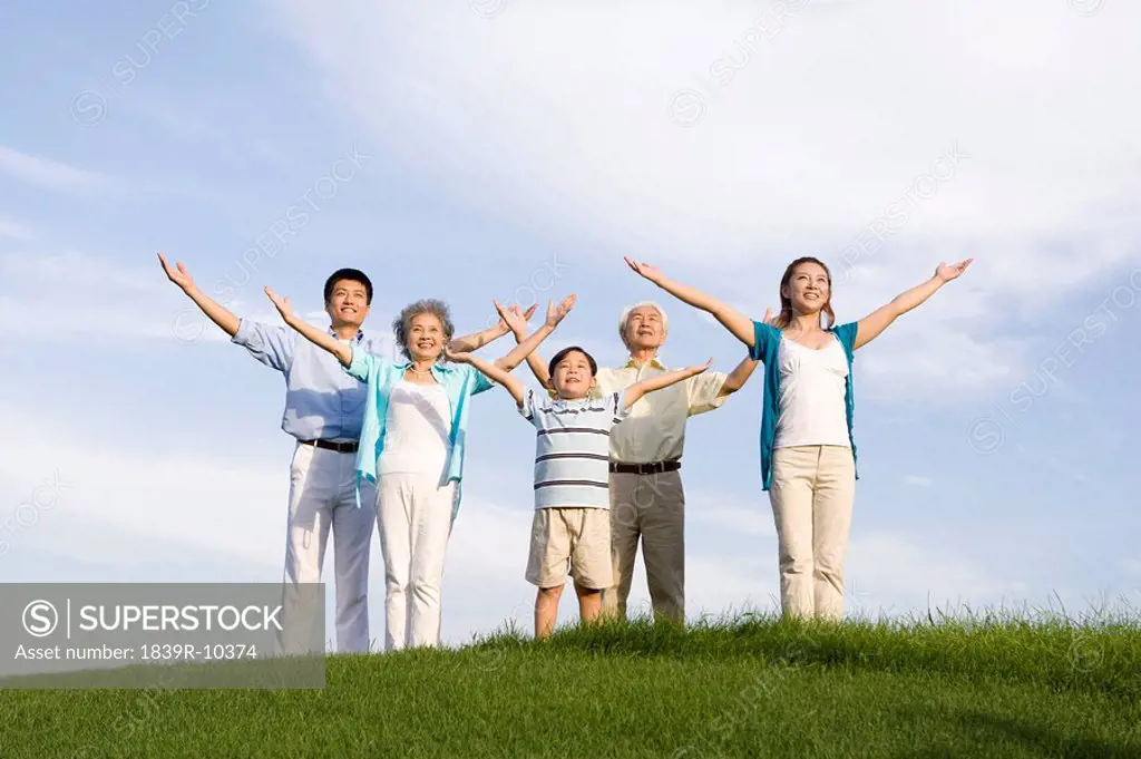 Family standing on the grass, arms out_stretched
