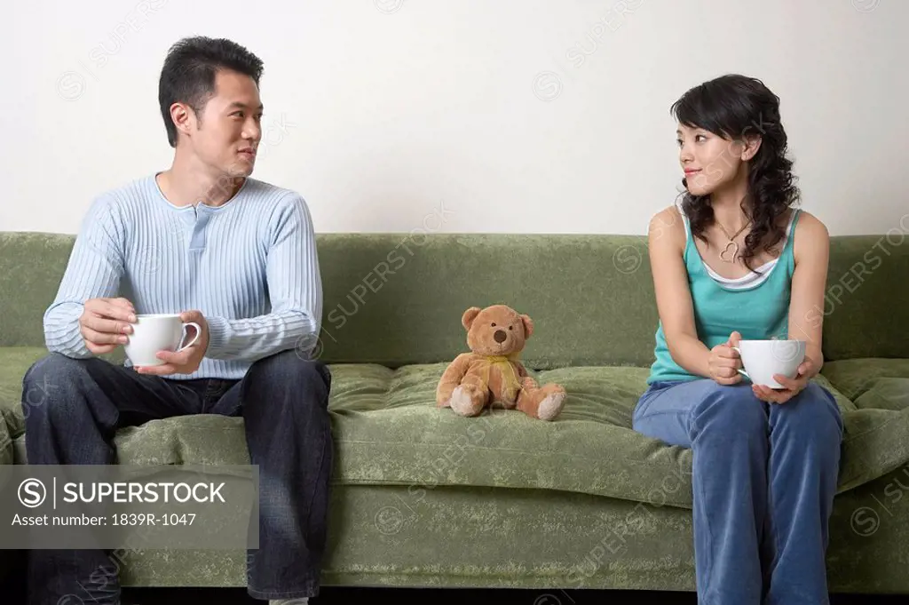 Young People Sitting On Couch Together, Drinking Tea