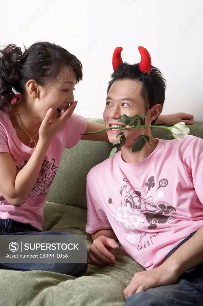 Man Wearing Devil Horns, Holding Rose In His Teeth