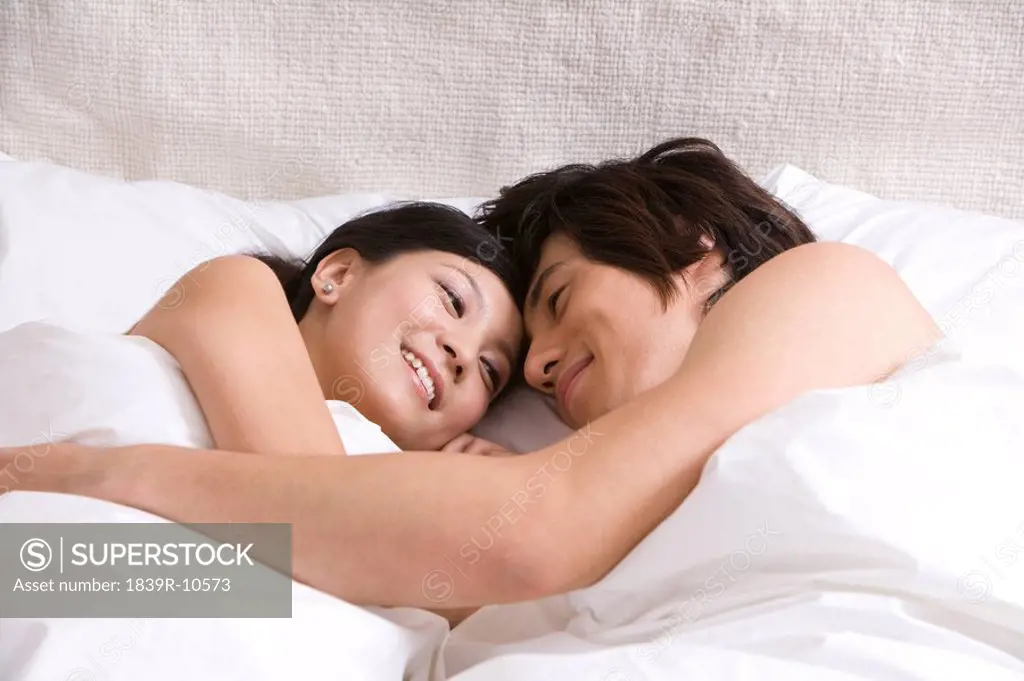 Asian couple cuddling on bed