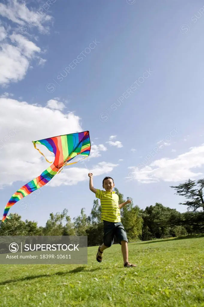 Young boy running with kite outdoors
