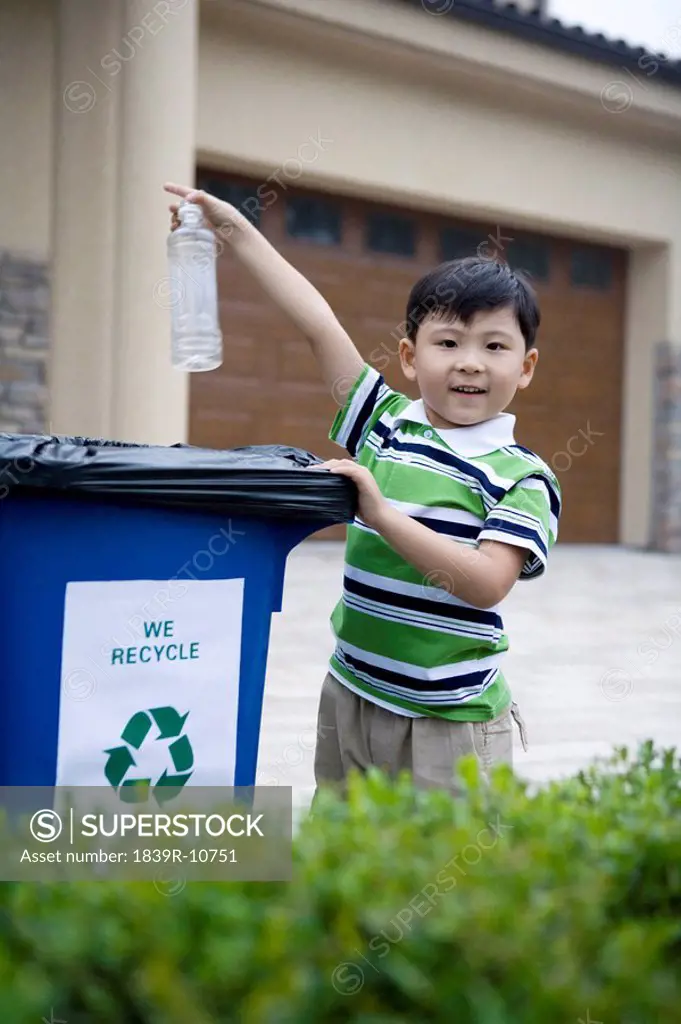 Young boy throwing bottle into recycle box