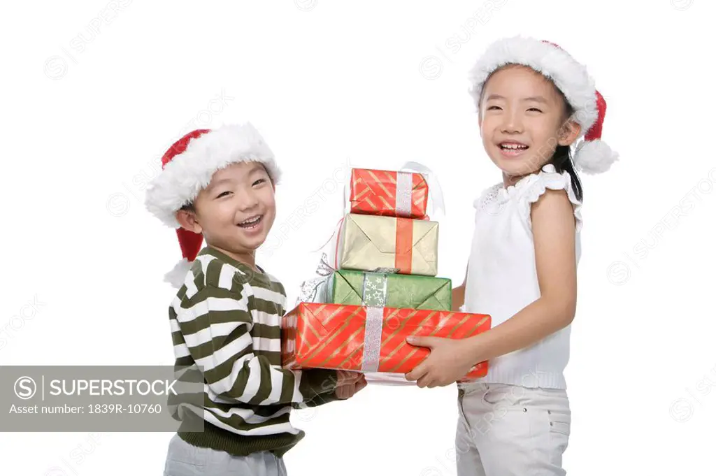 Boy and girl with Santa hats holding gift box