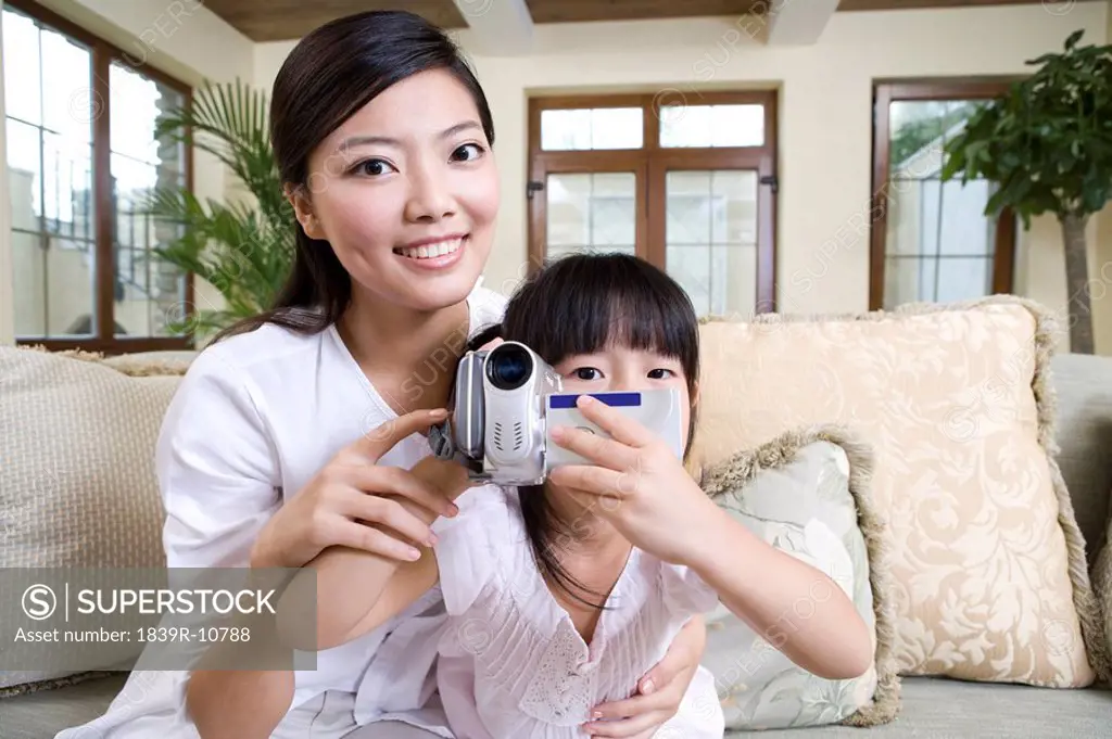 Mother and daughter using digital video camera