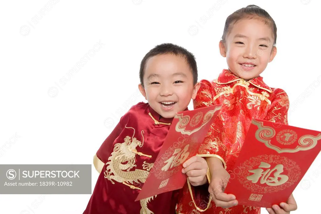 Boy and girl in Chinese traditional clothes holding red envelopes