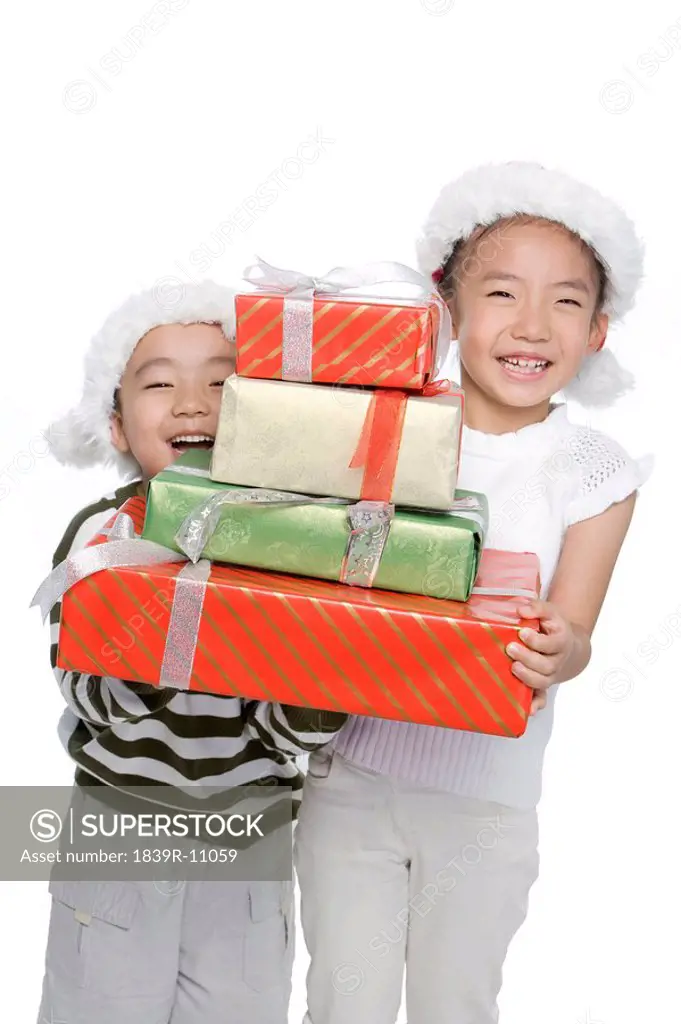 Boy and girl with Santa hats holding gift box