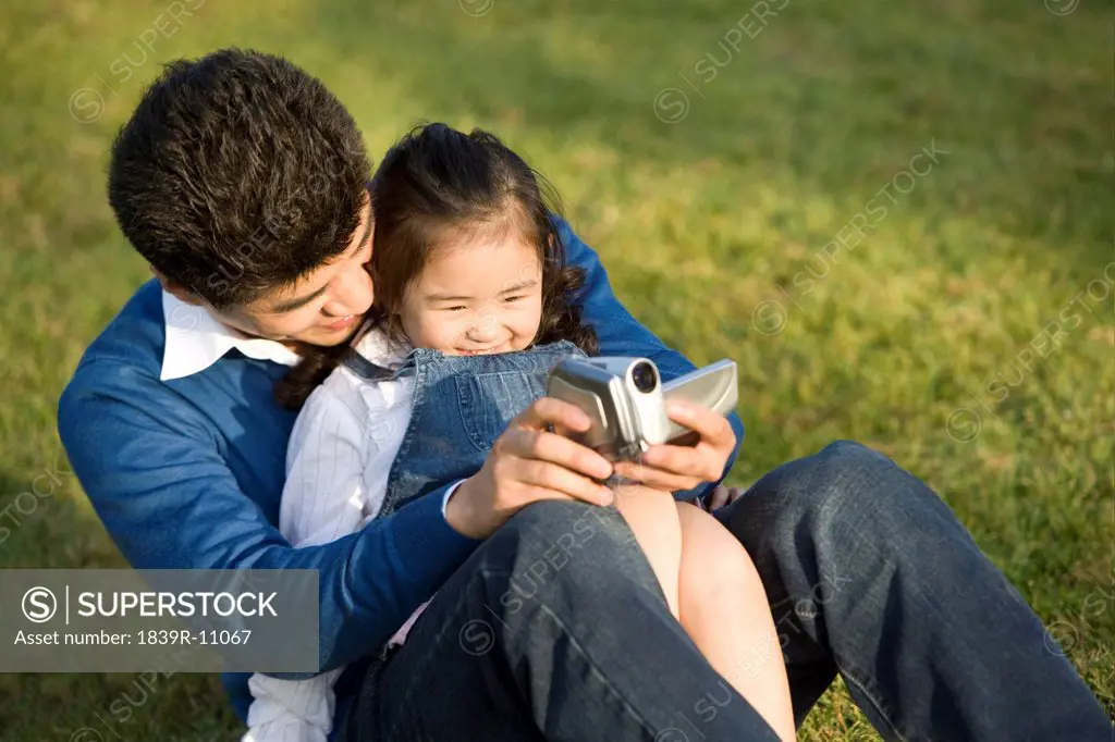 Father and daughter making a home video at the park