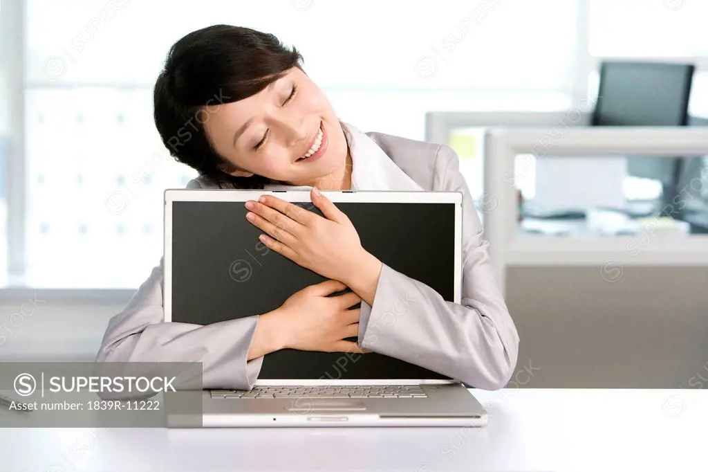 Office worker hugging her computer