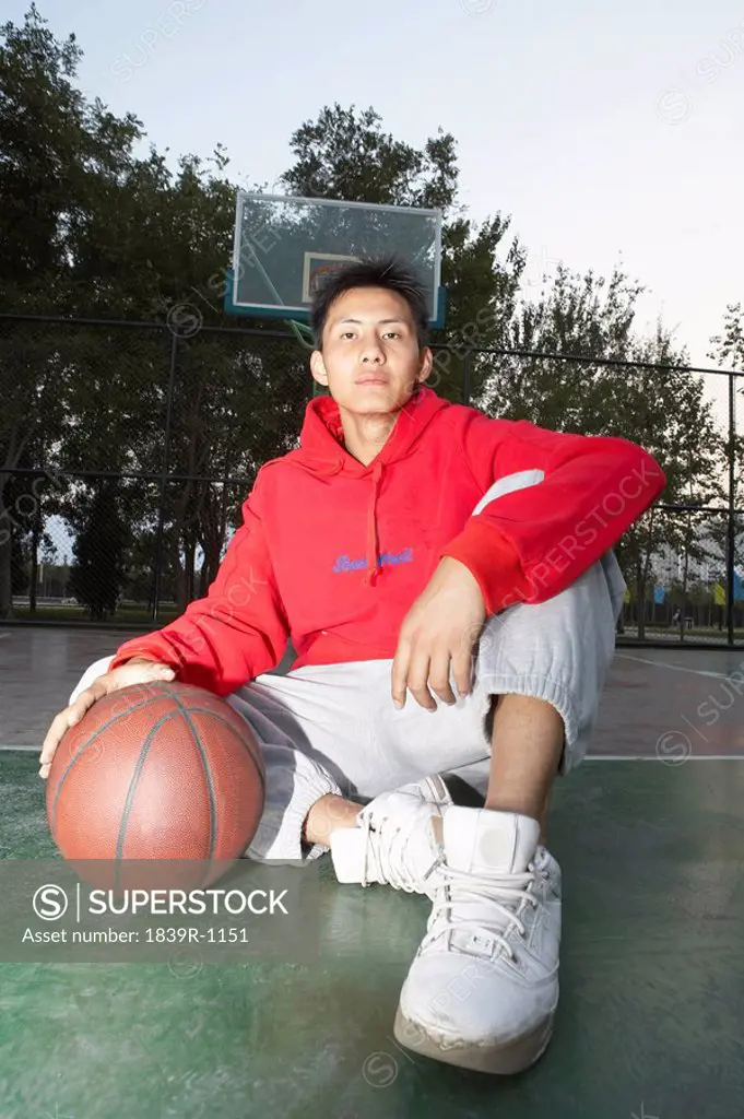 Young Man Sitting On A Basketball Court