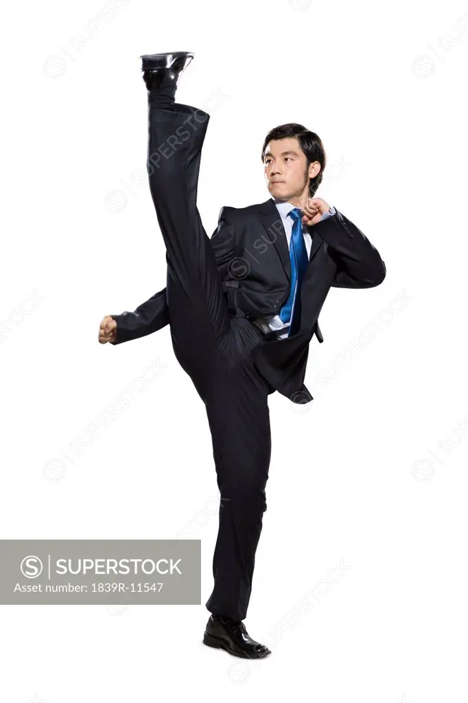 Businessman fighting stance with leg in the air