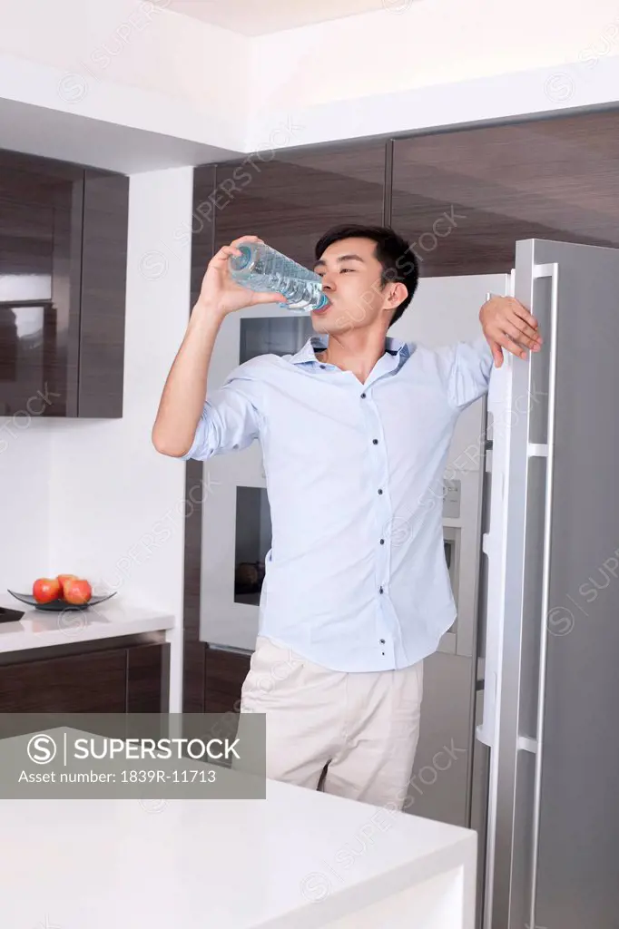 Man drinking a bottle of water in the kitchen