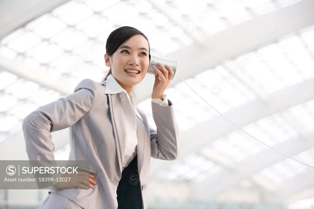 Businesswoman using tin can phone