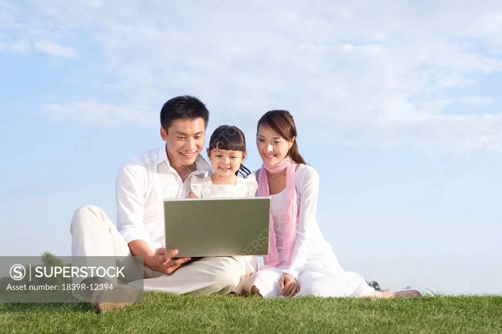 A young family using a laptop outdoors