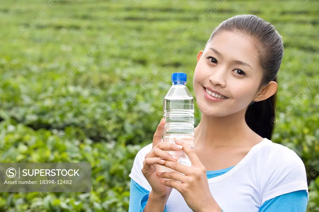 Young Woman in Tea Field with a Bottle of Water