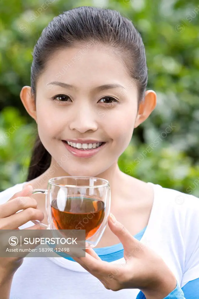 Young Woman Drinking Tea in a Tea Field