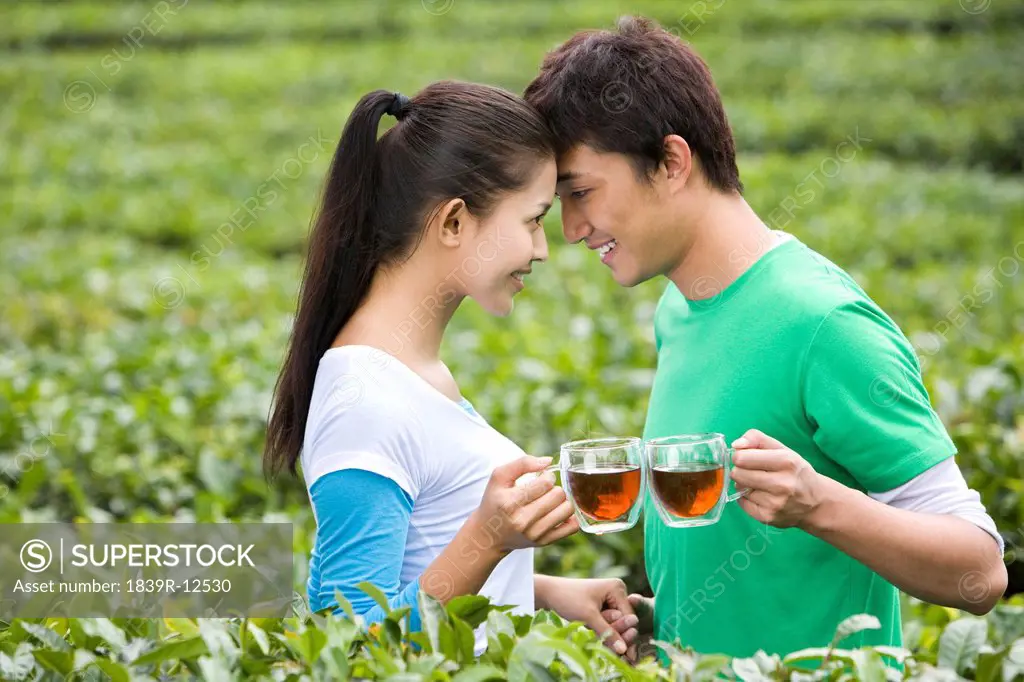 Young Couple in Tea Field with Freshly Brewed Tea