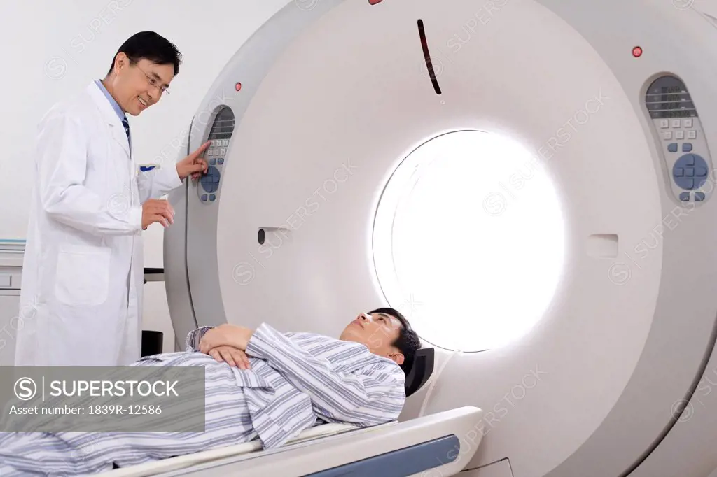 Medical professional helping a patient into a MRI scanner