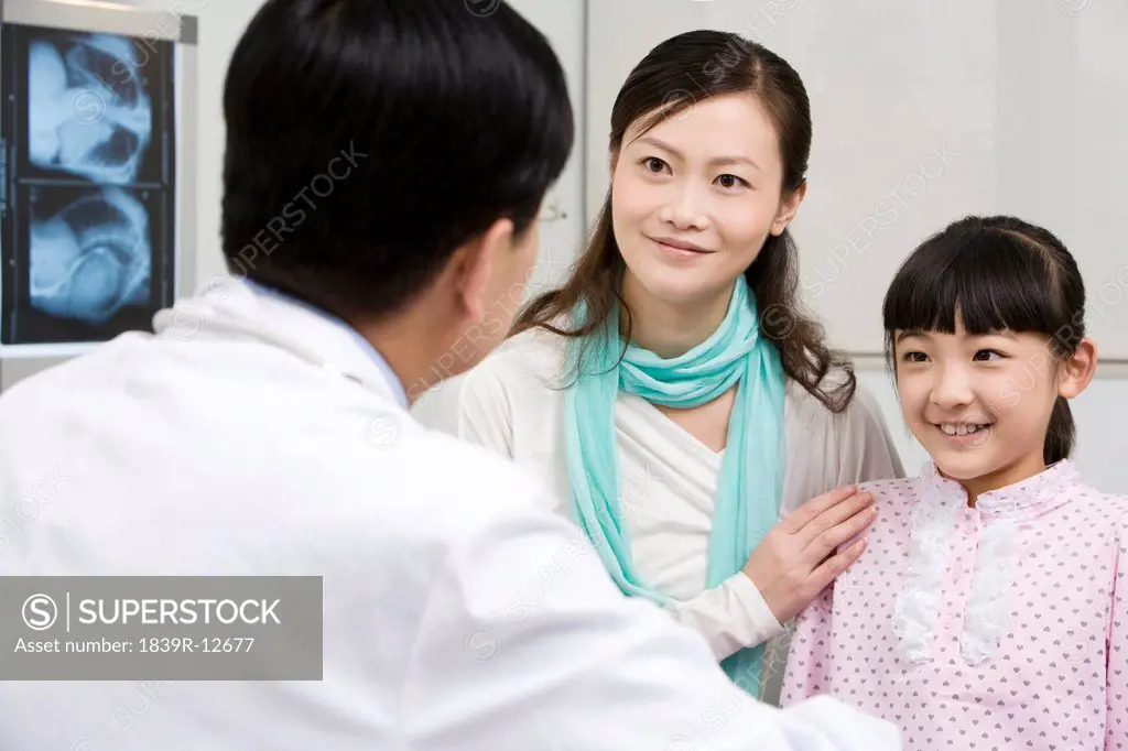 Doctor speaking with his young patient and her mother
