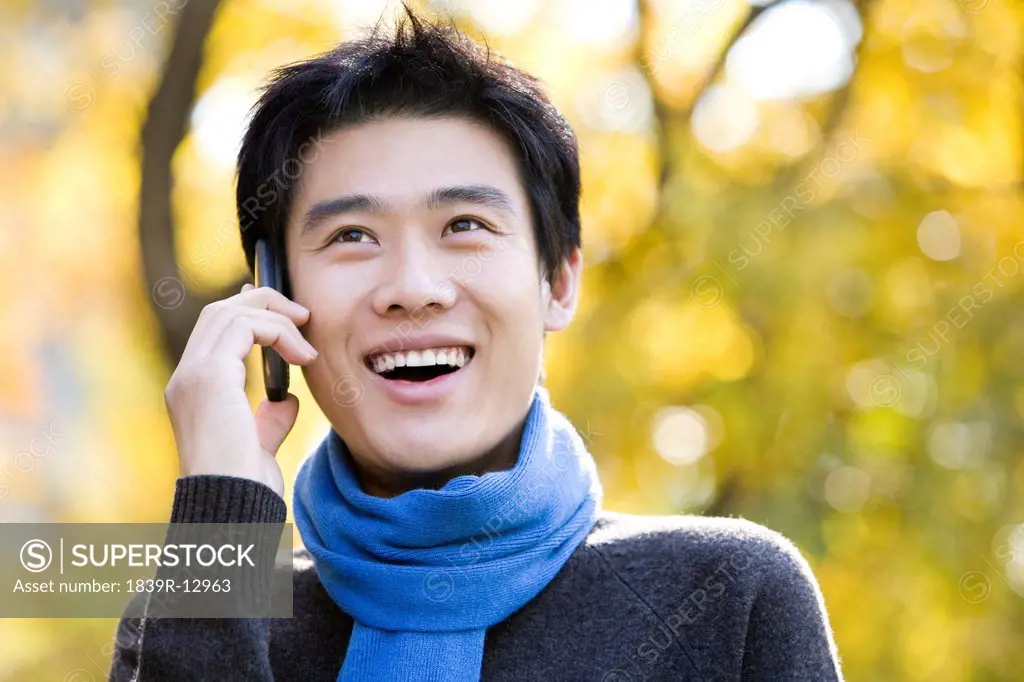 Young Man Talking on a Mobile Phone in a Park