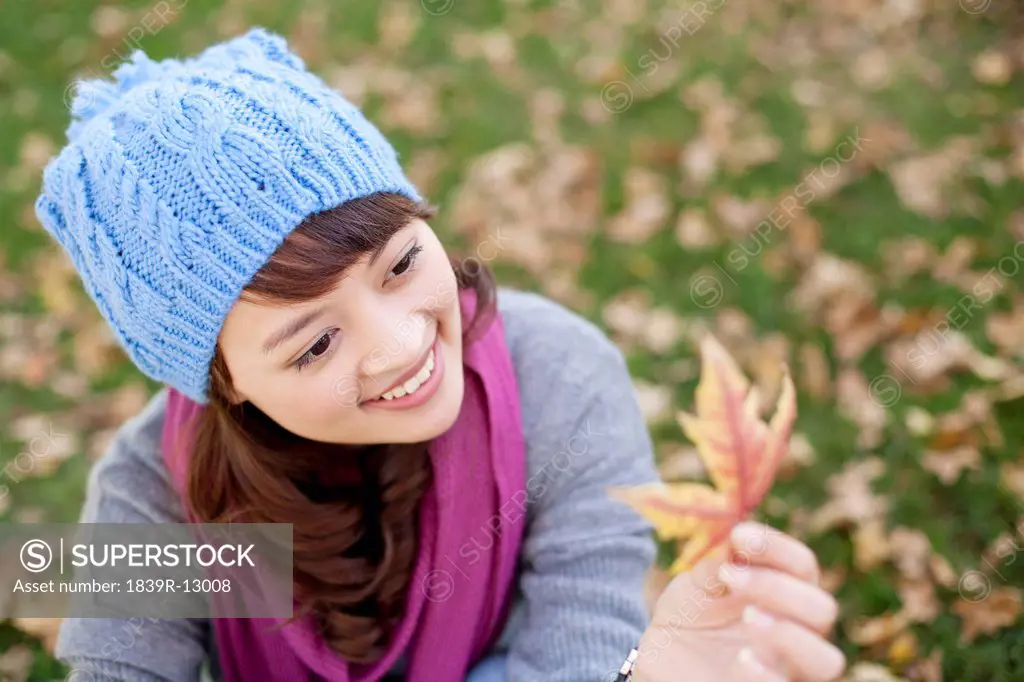 Young Woman Looking At Maple Leaf